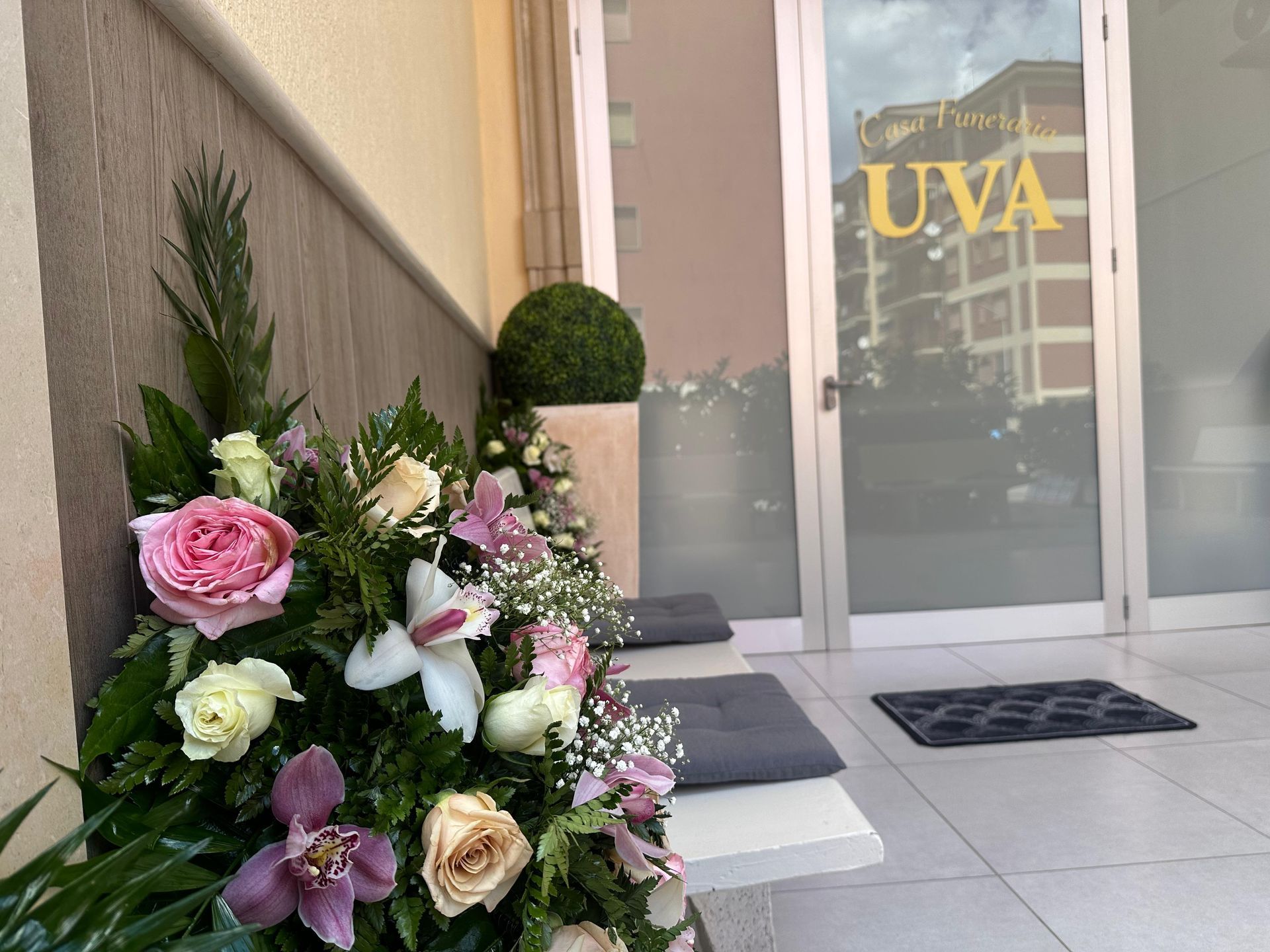 Un mazzo di fiori davanti a una porta con la casa funeraria uva