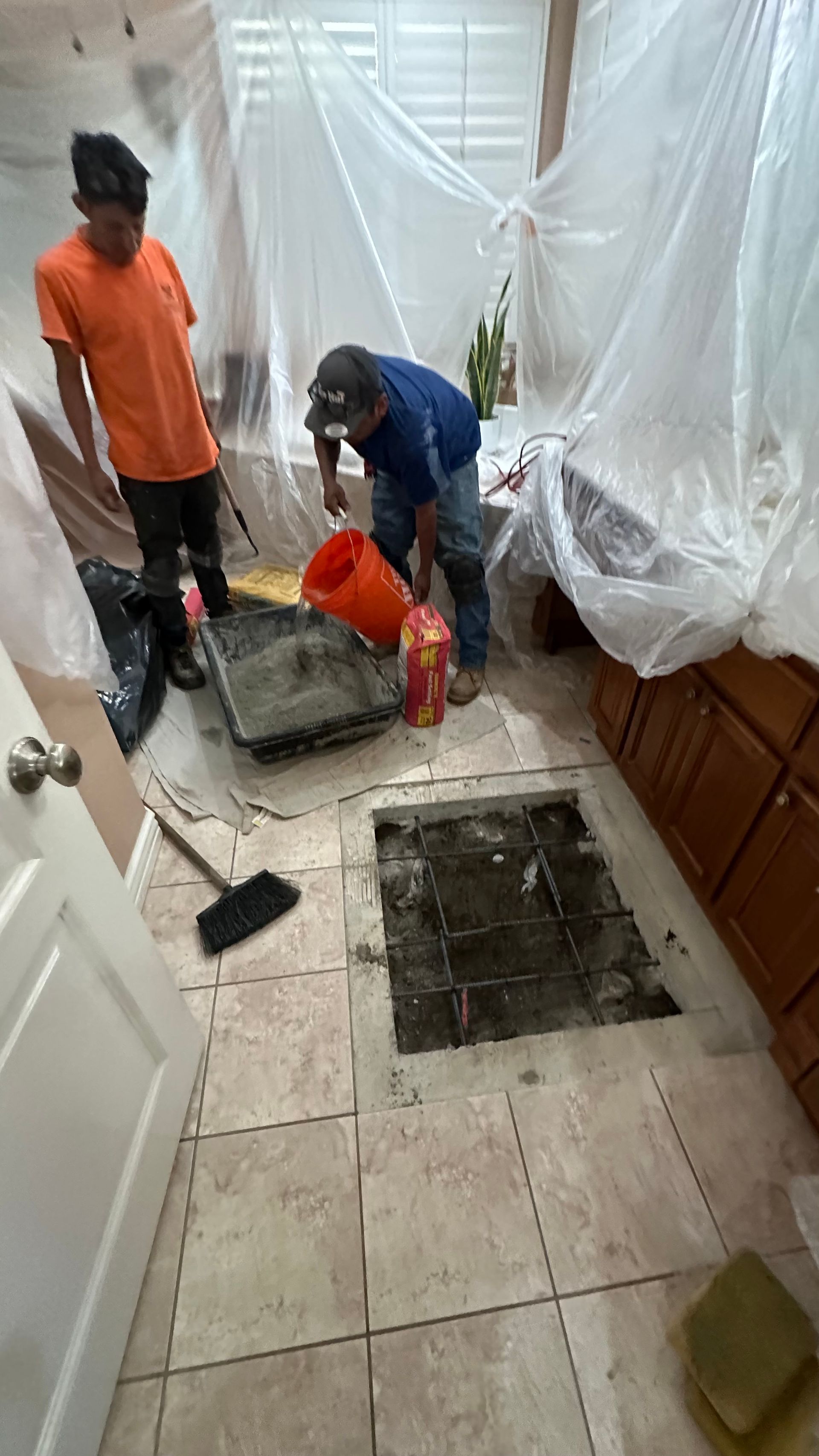 Two Men Are Working on A Bathroom Floor.
