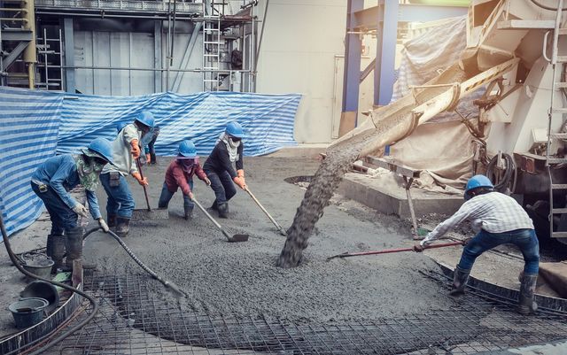 A group of construction workers are working on a concrete floor.