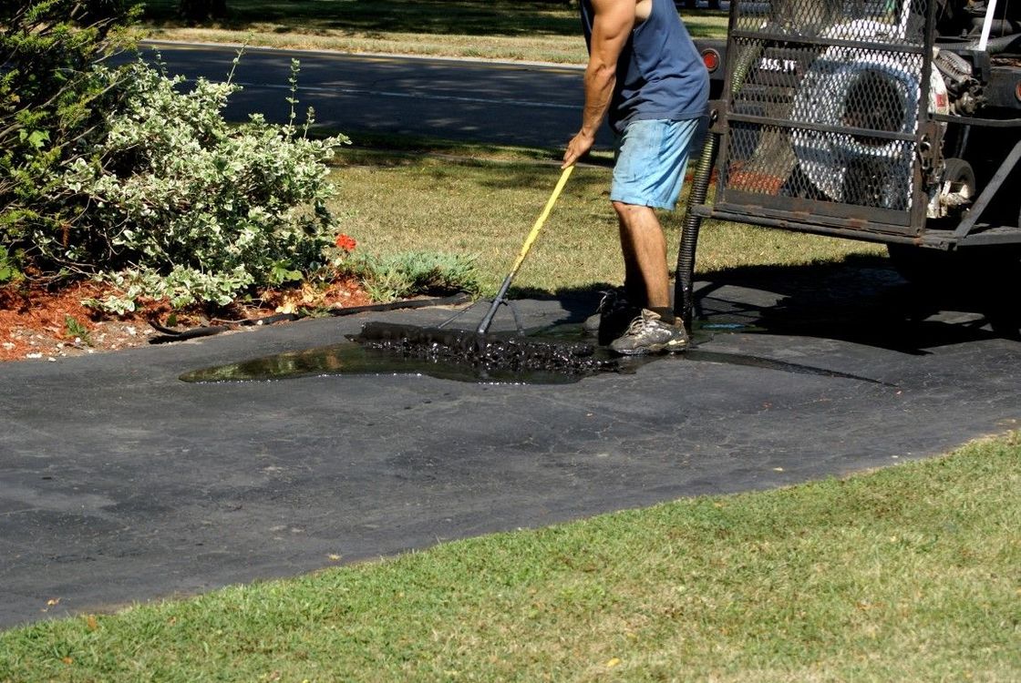 A man is cleaning a driveway with a broom.