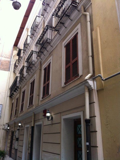 Facciata di palazzo giallo con persiane in legno