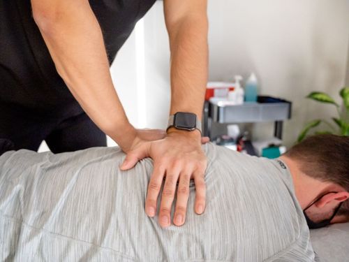 a man in a blue scrub is giving a man a neck massage .