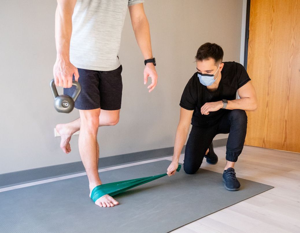 a man in a blue shirt is applying kinesio tape to a man 's knee
