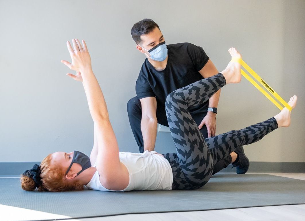 a man wearing a mask is helping another man with his back