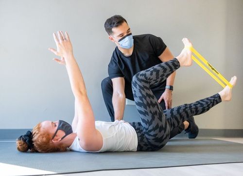 a man wearing a mask is helping another man with his back