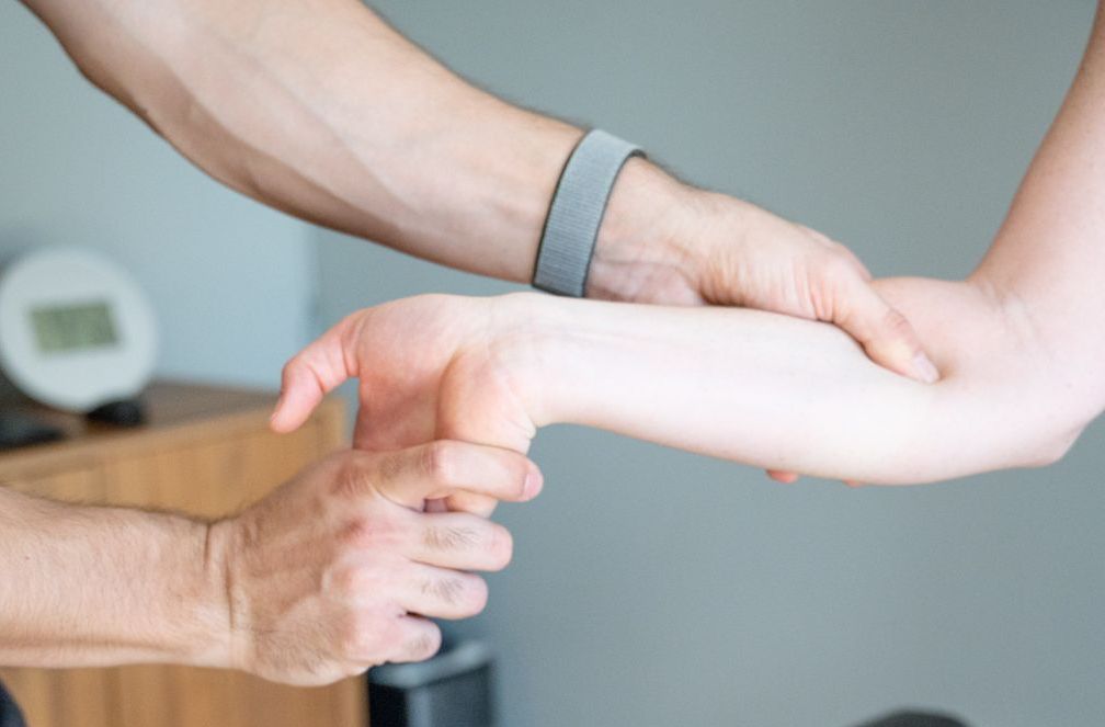 a man in a blue shirt is applying kinesio tape to a man 's knee