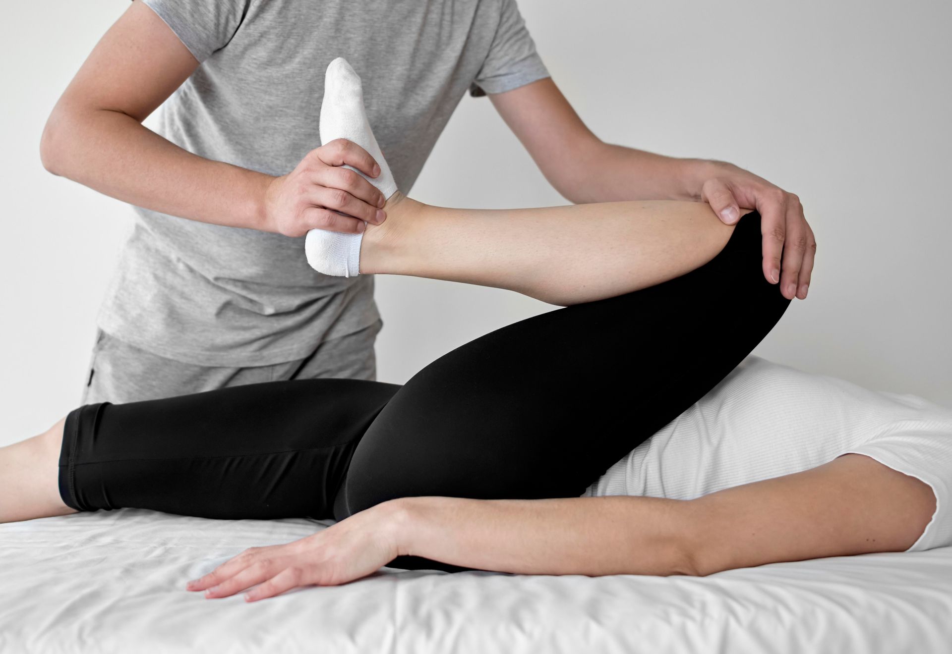 a man is stretching a woman 's leg on a bed .