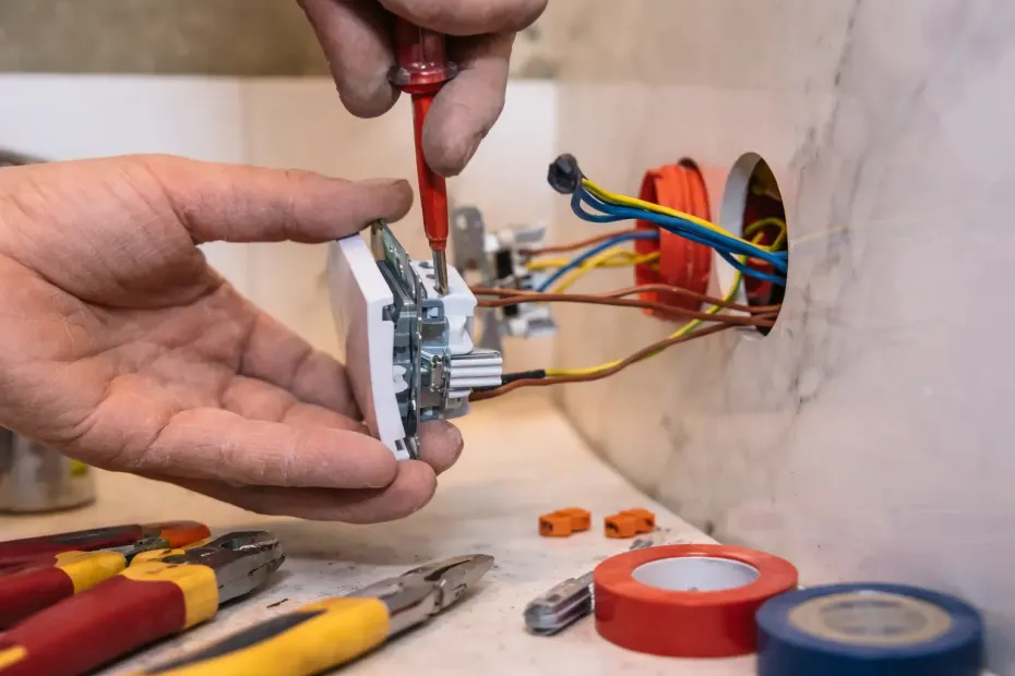 Deux mains utilisent un tournevis pour connecter des fils de couleur