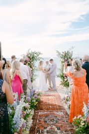 A bride and groom are getting married in front of a crowd of people on a beach.