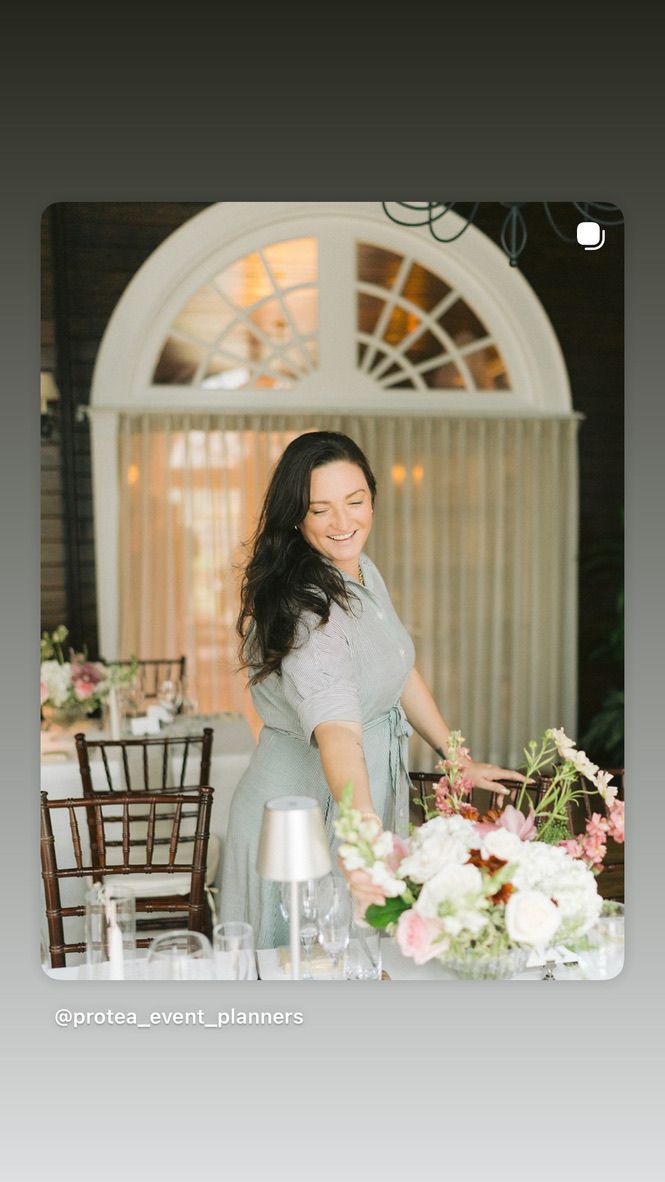 A woman in a black shirt is smiling while sitting at a table.