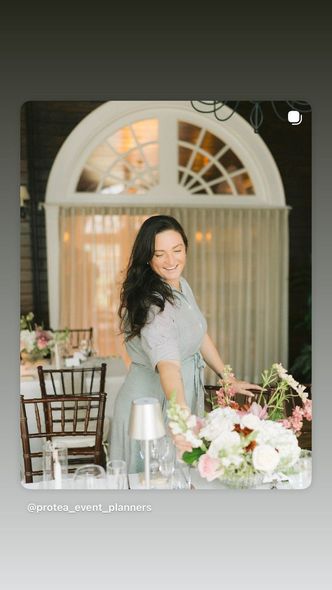 A woman in a black shirt is smiling while sitting at a table.