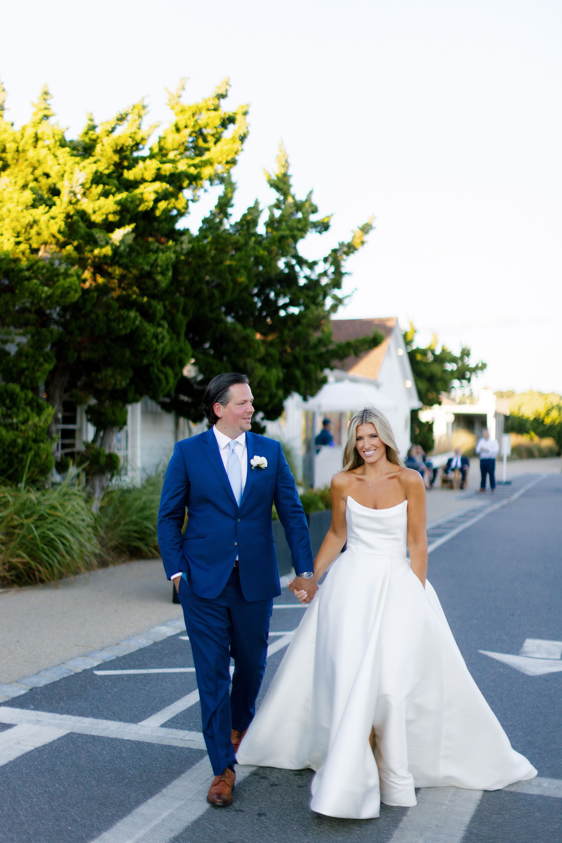 A bride and groom are walking on the beach.