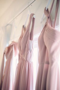 A row of pink bridesmaid dresses hanging on a rack.