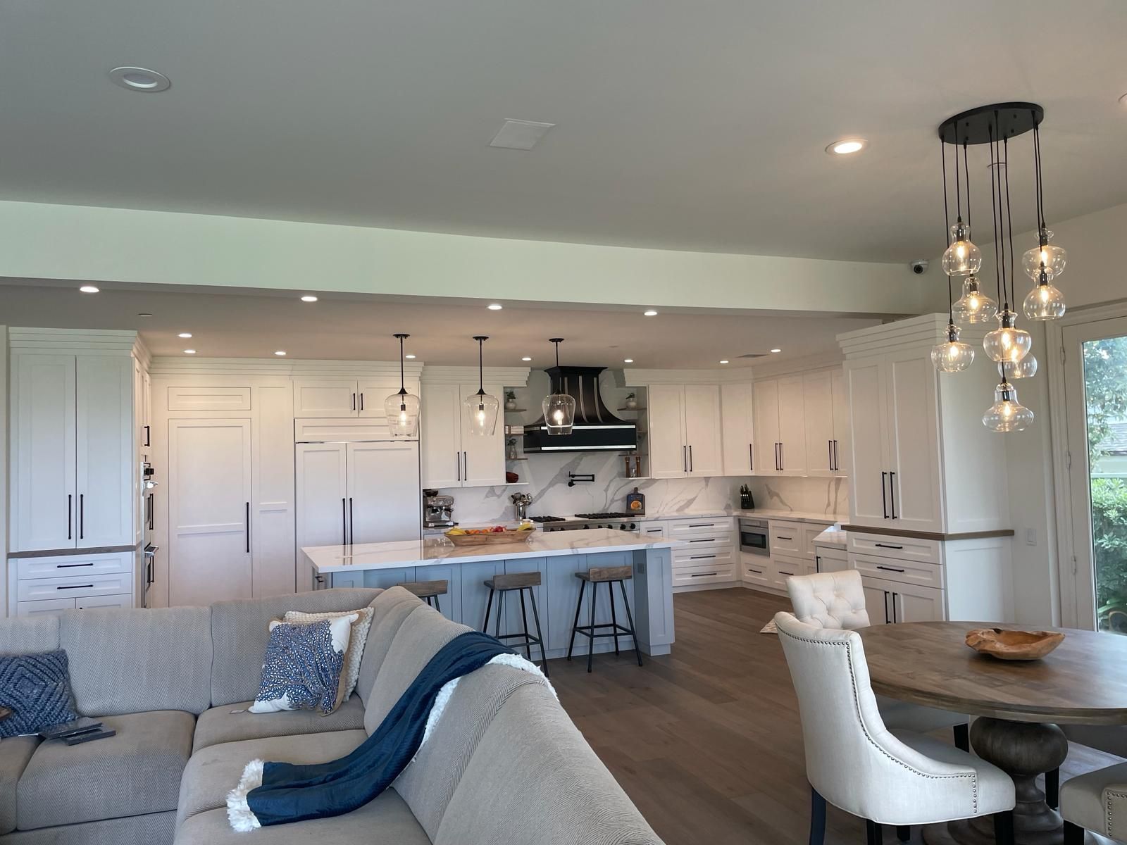 Spacious modern kitchen with white cabinets, blue island, and open-plan living area.