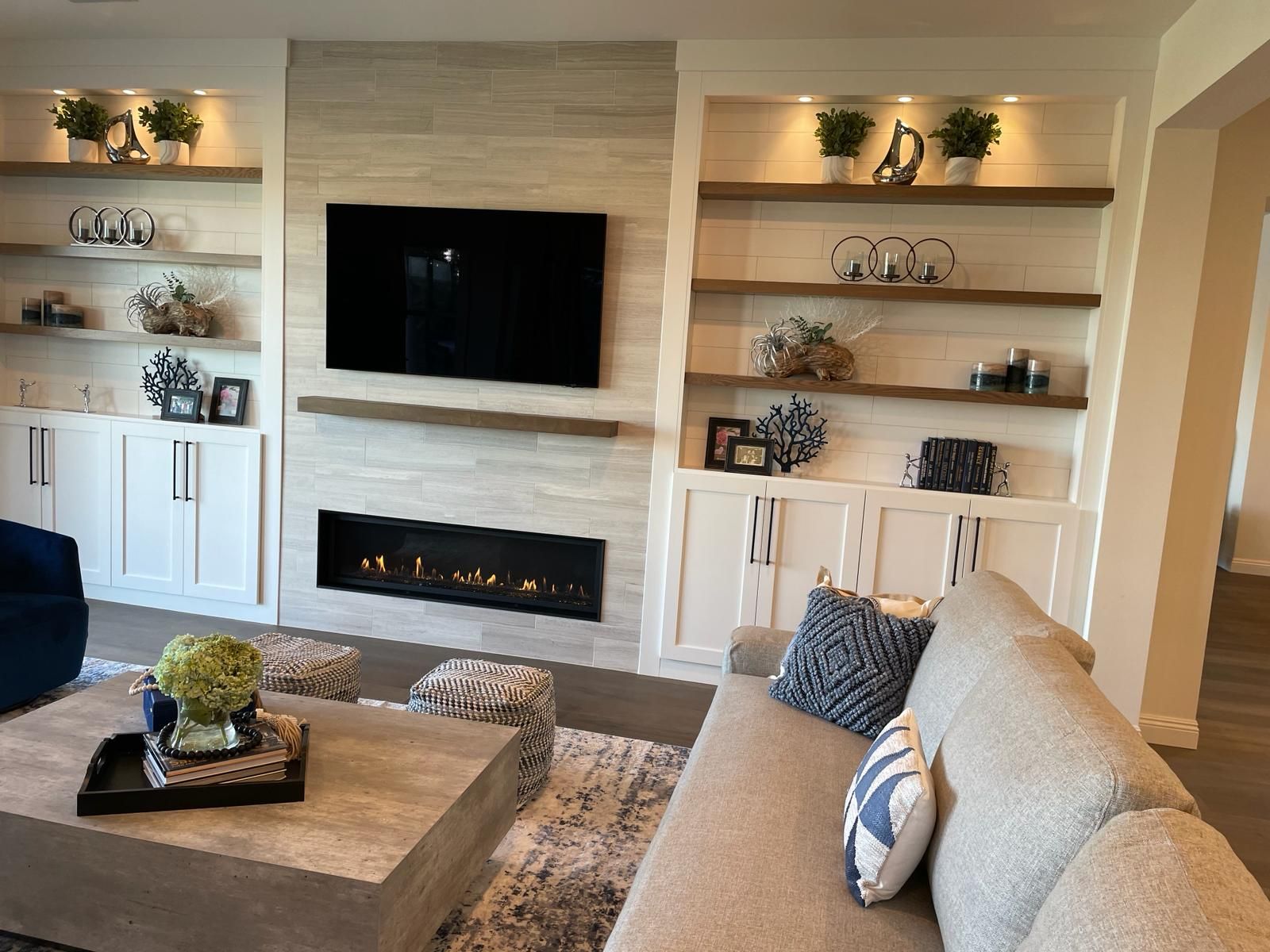 Living room with fireplace, built-in shelves, TV, and neutral-toned furniture.
