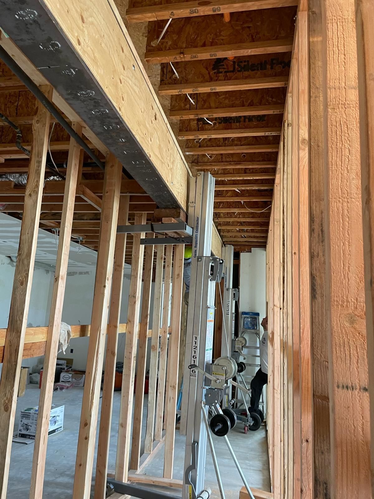 Wooden framing with a large beam supported by metal posts; construction site interior.