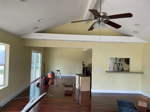 Interior of a room with hardwood floors and light yellow walls. A ceiling fan hangs from a vaulted ceiling.