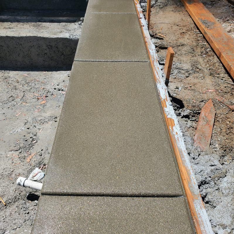 Freshly poured concrete border alongside wooden planks and steps.