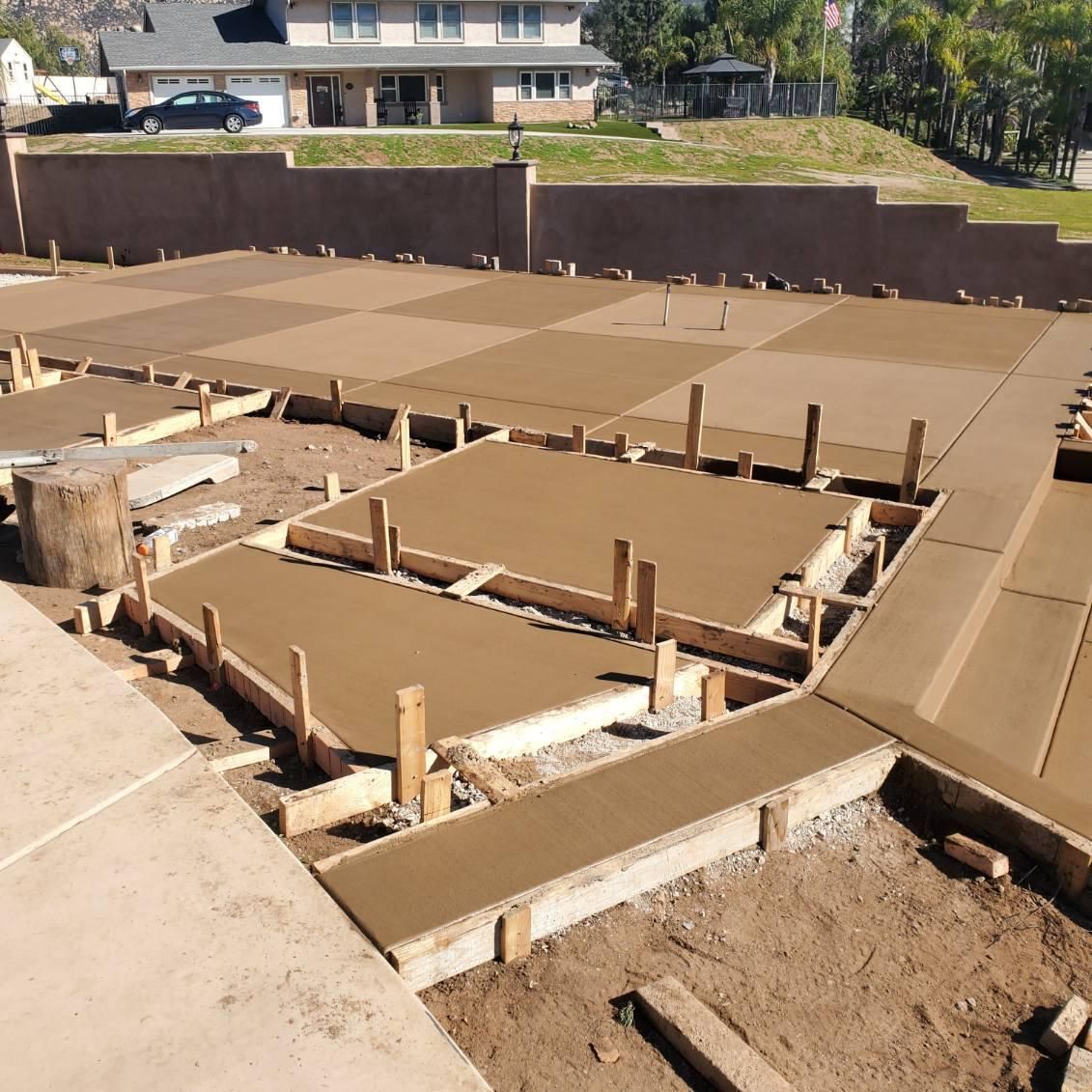 Freshly poured concrete slabs in various sections, ready for a patio or walkway; wood framing visible.