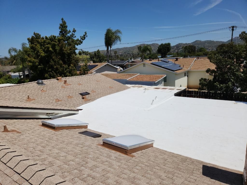 View of multiple homes with various roof types under a sunny sky.