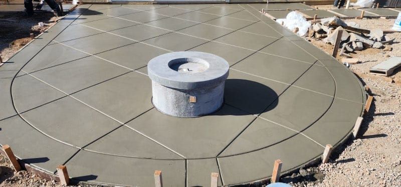 Concrete patio with a circular fire pit under construction.