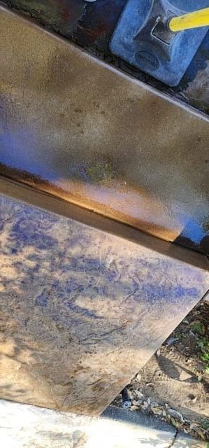 Close-up of weathered surface with blue and brown hues, near a stone ground.