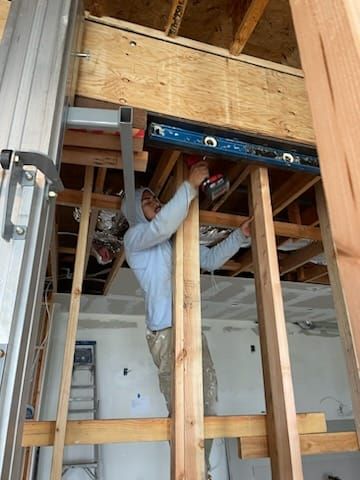 Construction worker using a power drill on a wooden frame.