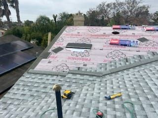Roof being repaired with new shingles, underlayment, and tools. Grey and black.