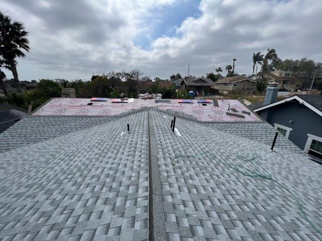 Newly installed gray shingle roof with some areas still under construction.
