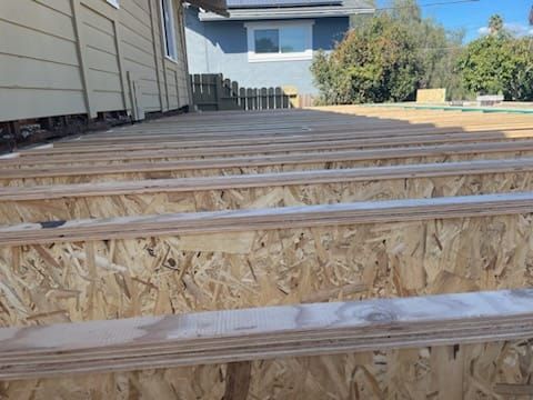 Wooden deck under construction, showing oriented strand board (OSB) joists and decking.