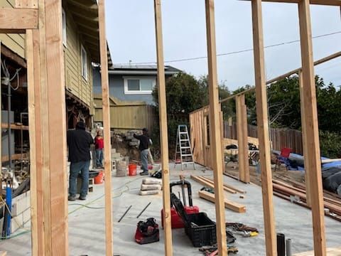 Construction site with framing; workers building near a house.