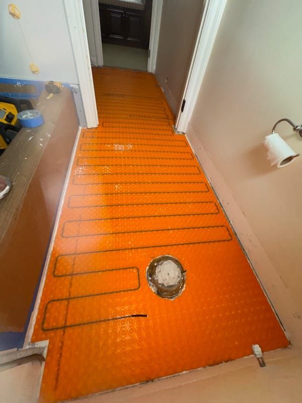 Orange electric floor heating system installed in hallway.