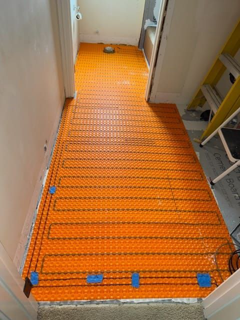 Orange electric radiant floor heating system installed in a hallway, ready for tile installation.