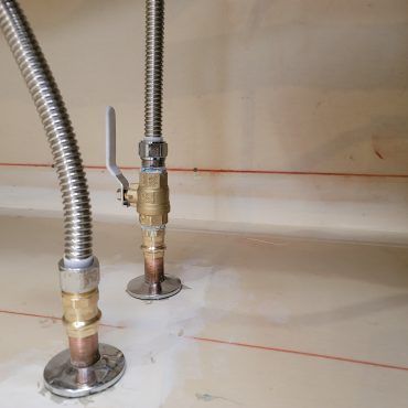 A close up of two stainless steel pipes with valves attached to them.