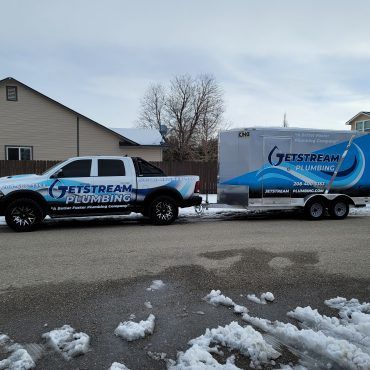 A jetstream plumbing truck is parked next to a trailer.