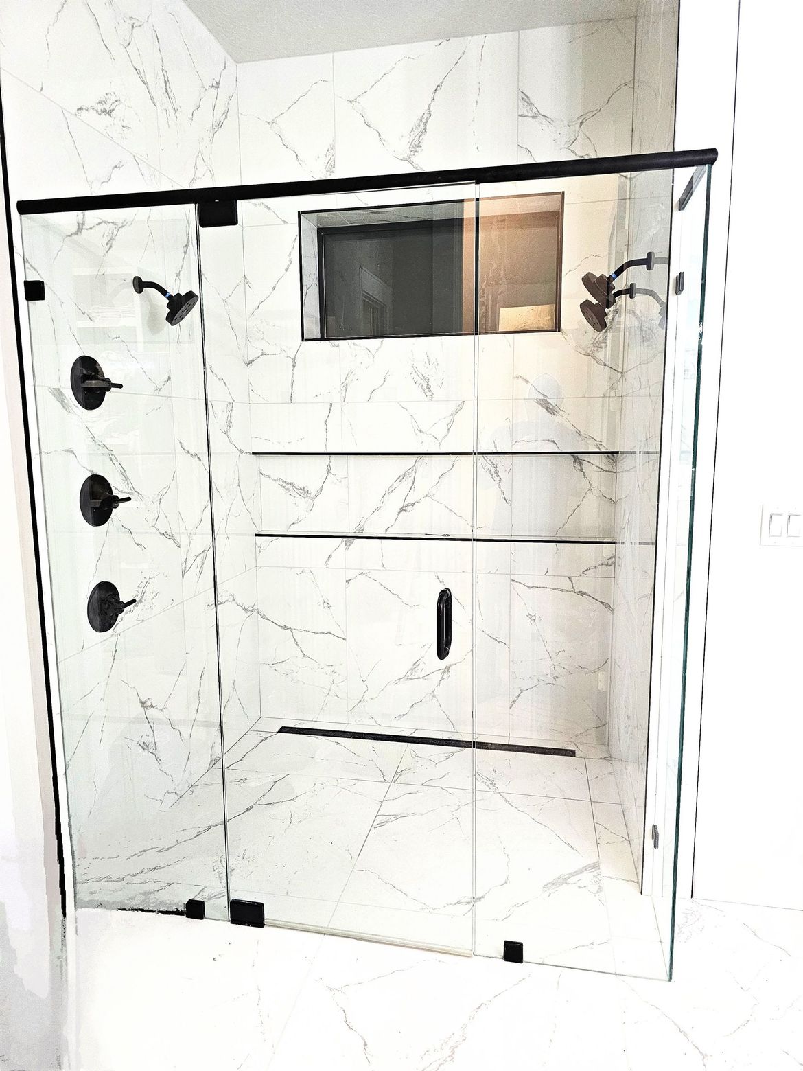 A bathroom with marble tiles and a sliding glass shower door.