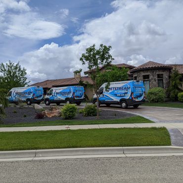 Three vans are parked in front of a large house.