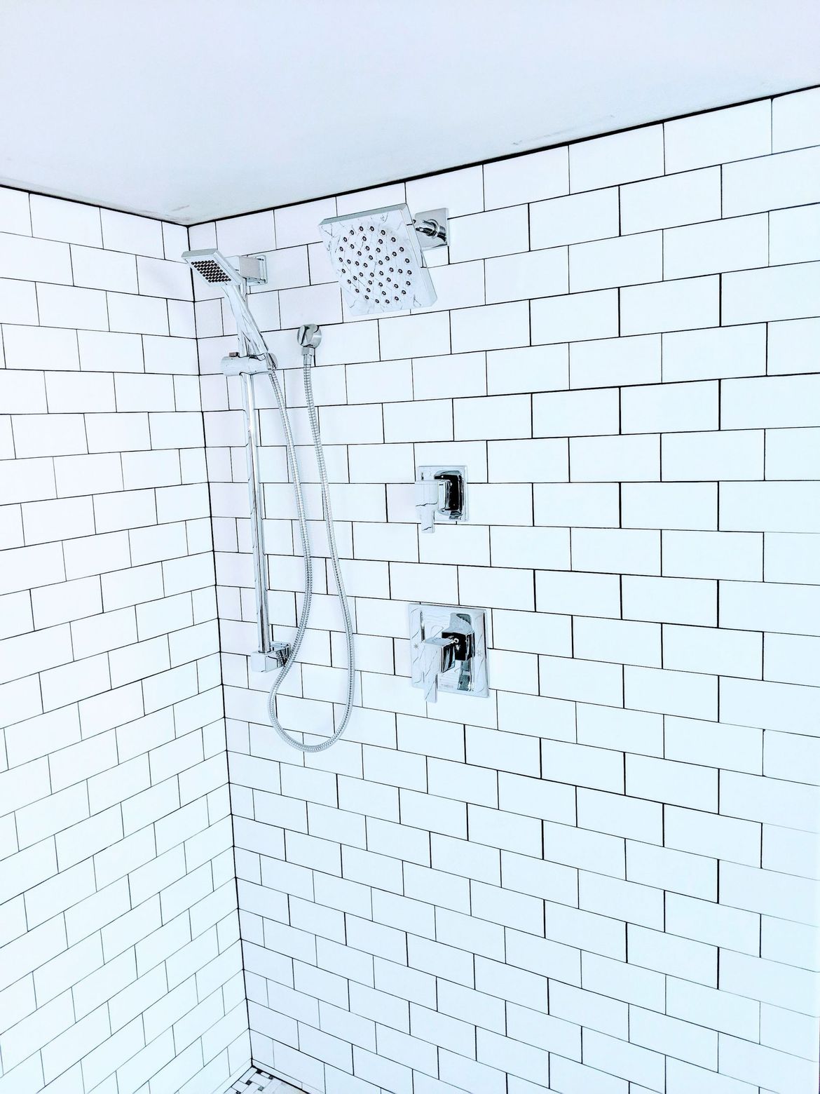 A shower with a white brick wall and a shower head.