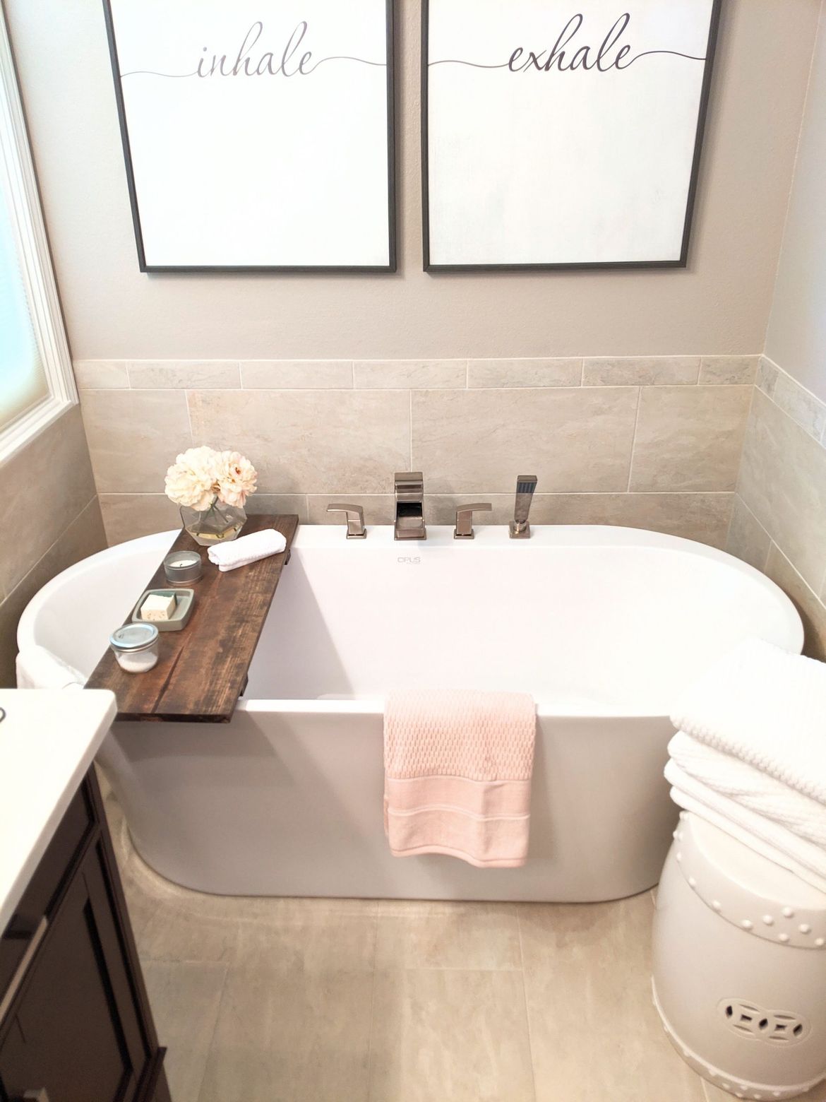 A bathtub with a wooden tray on top of it in a bathroom.