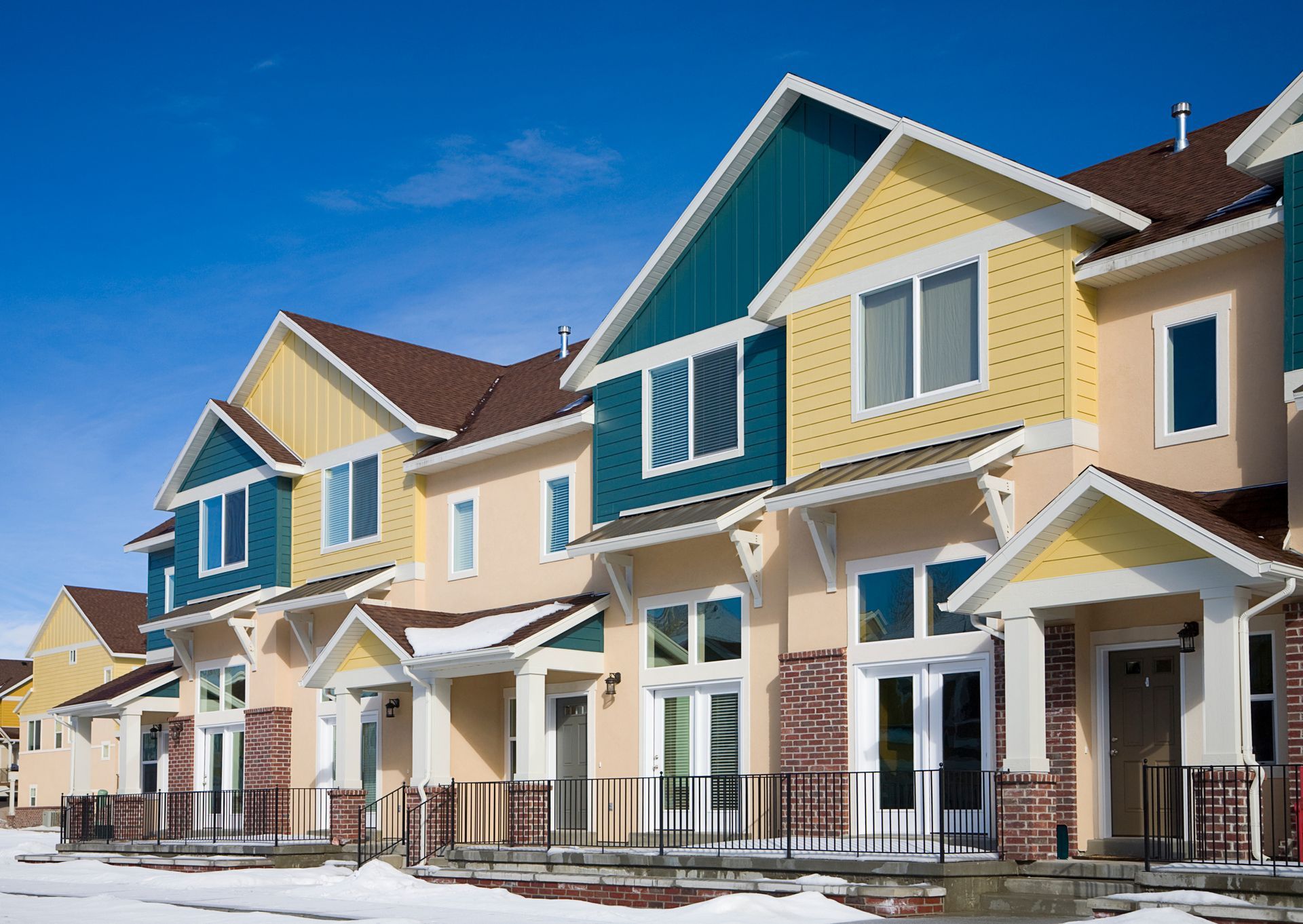 A row of houses with snow on the ground in front of them