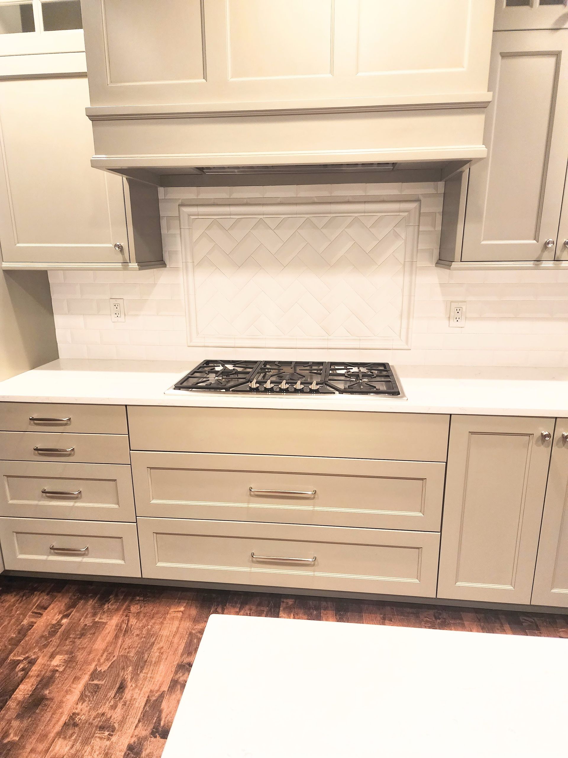 A kitchen with white cabinets and a stove top oven.