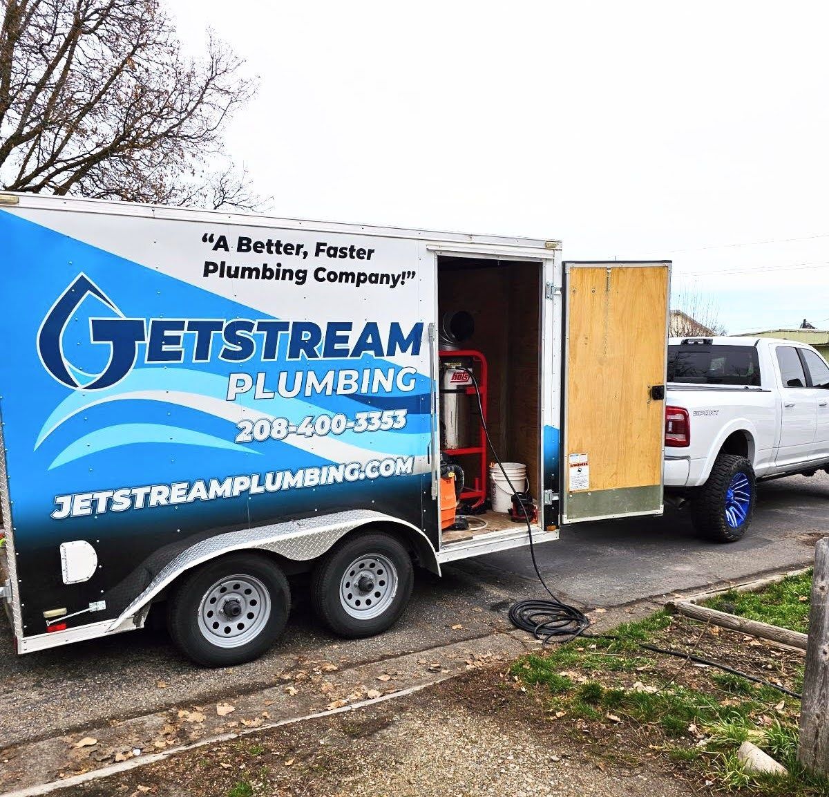A jetstream plumbing truck is parked on the side of the road.