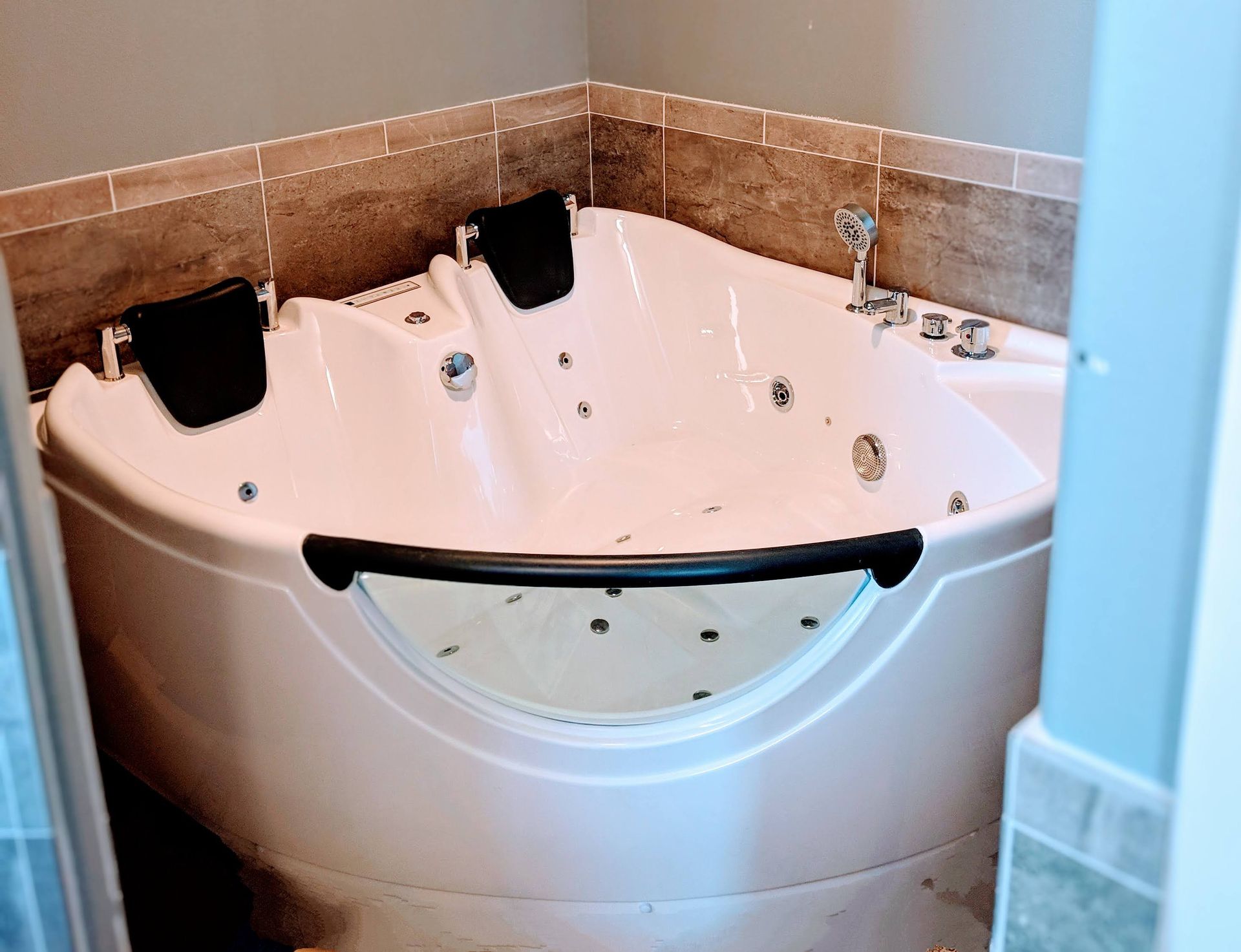 A white jacuzzi tub in a bathroom next to a window