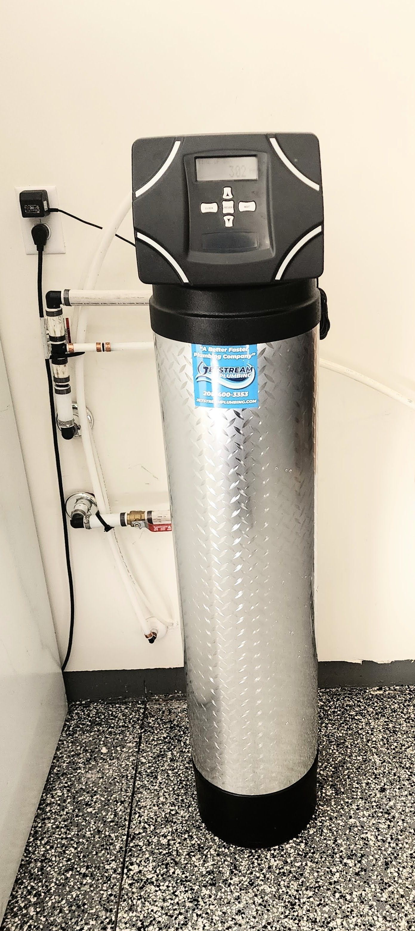 A stainless steel water filter is sitting on the floor in a room.