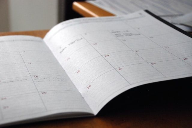 Open monthly planner calendar on a desk, showing scheduled dates and appointments, Wauwatosa, WI.