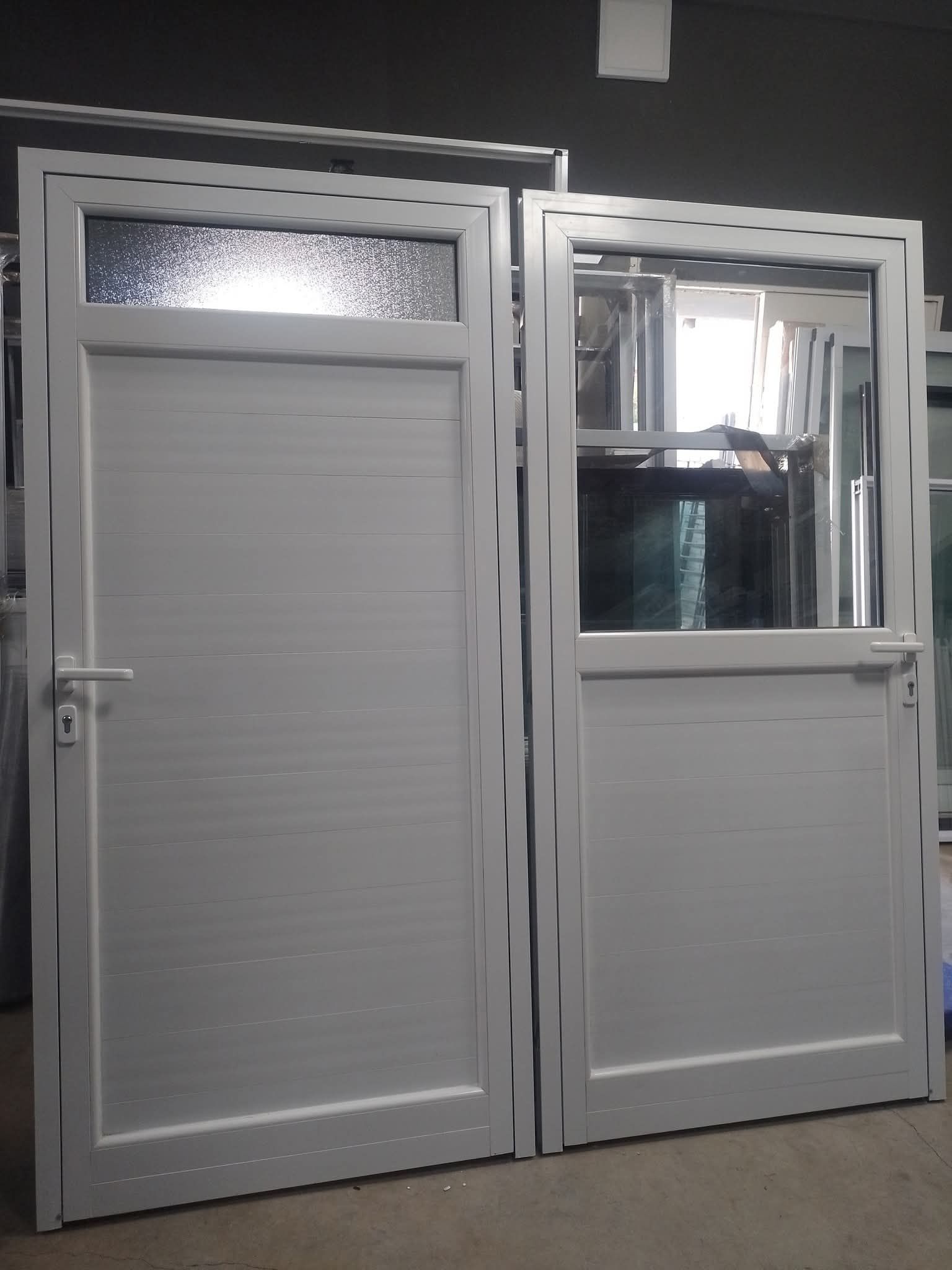 Puertas blancas de doble panel con paneles superiores de vidrio, en interiores. Una puerta tiene una ventana de vidrio texturizado.