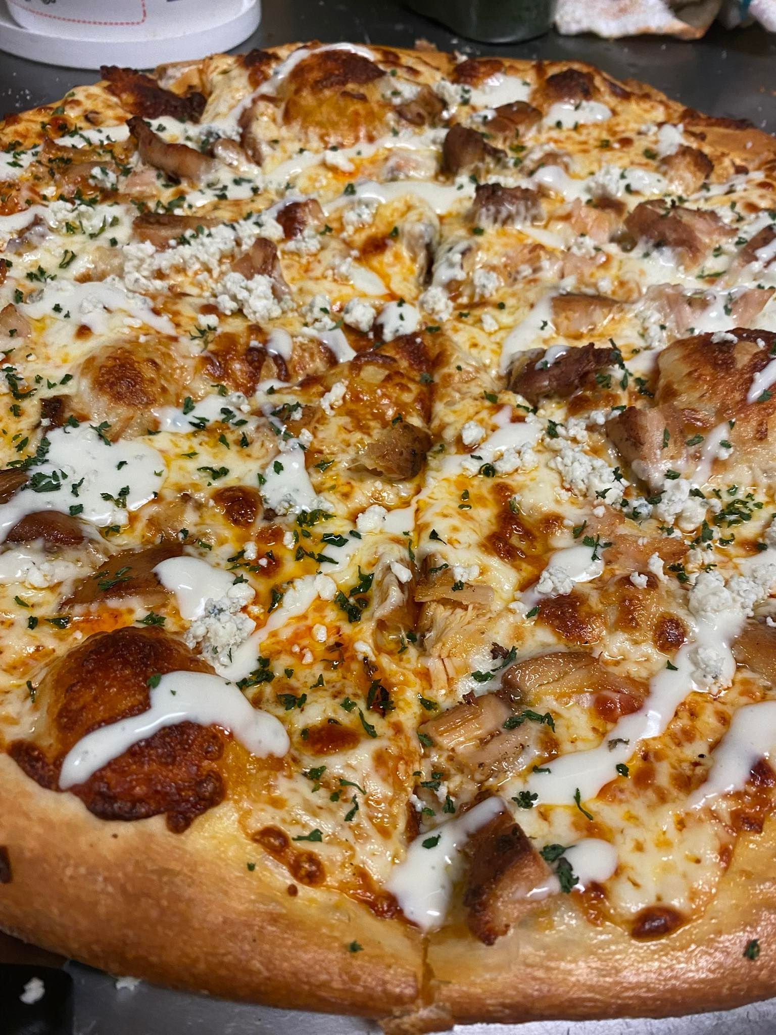 Pizza with chicken, mozzarella, and drizzle of white sauce, cut into slices.