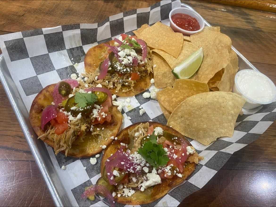 Tacos with toppings, chips, salsa, and sour cream on a tray.