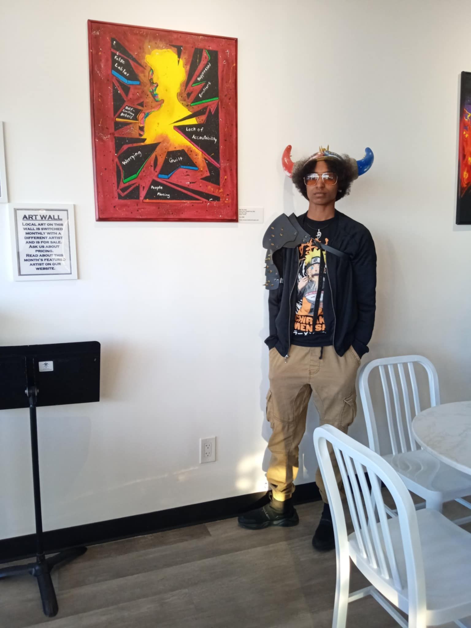 A man wearing a horned hat is standing in front of a painting.