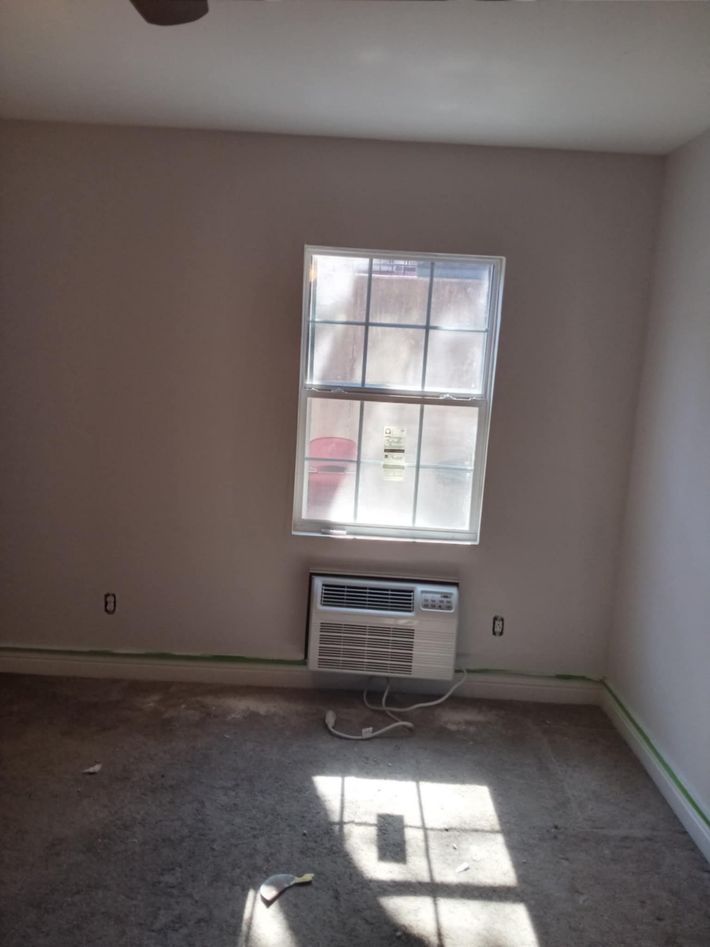 An empty room with a window and a ceiling fan.